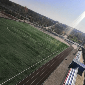 Спортивное покрытие - искусственная трава на спортивном стадионе и резиновые беговые дорожки